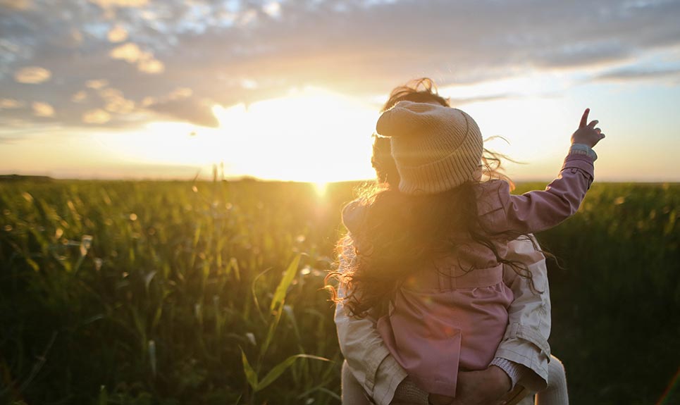 Mother and young daughter going on a walk in a rural field