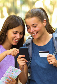 Two friends using a credit card to make a purchase on a mobile phone